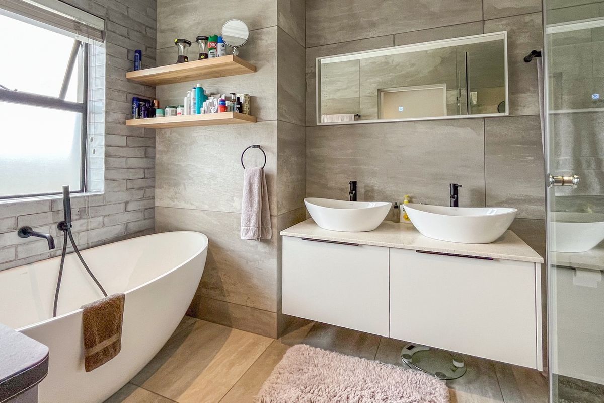 Modern bathroom featuring a freestanding bathtub, double vessel sink vanity with floating cabinetry, and a spacious walk-in shower with contemporary tile finishes.