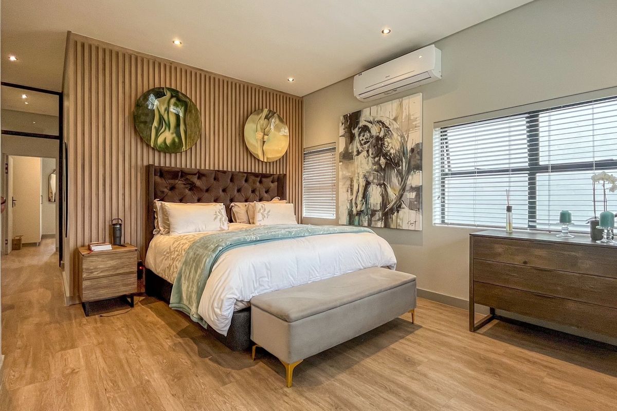 Modern bedroom featuring a timber slat feature wall, recessed lighting, split-system air conditioning, and durable laminate flooring.