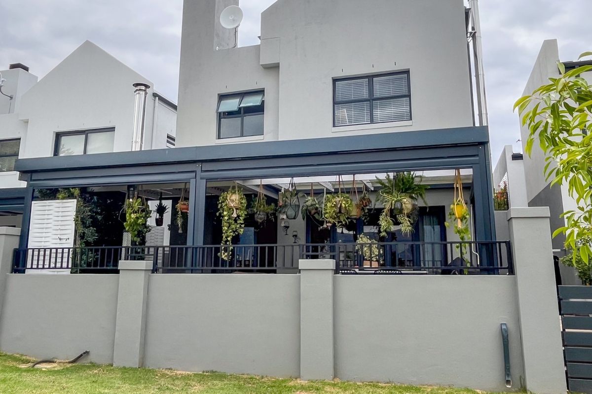 Rear view of the property featuring a modern covered patio with a metal pergola, secure balustrade, and well-maintained masonry boundary wall.
