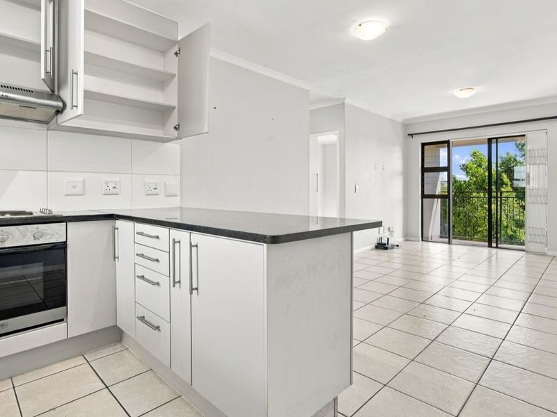 Open-plan kitchen and living area featuring tiled floors, built-in cabinetry, and direct access to a balcony through sliding glass doors.