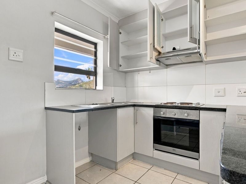 A functional kitchen featuring built-in cabinetry, laminate countertops, a built-in oven with hob, and a tiled splashback, offering a clean and practical workspace.