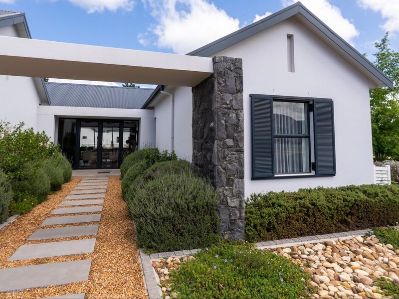 A modern front entrance featuring stone cladding, a metal roof, and a paved walkway leading to the main door.