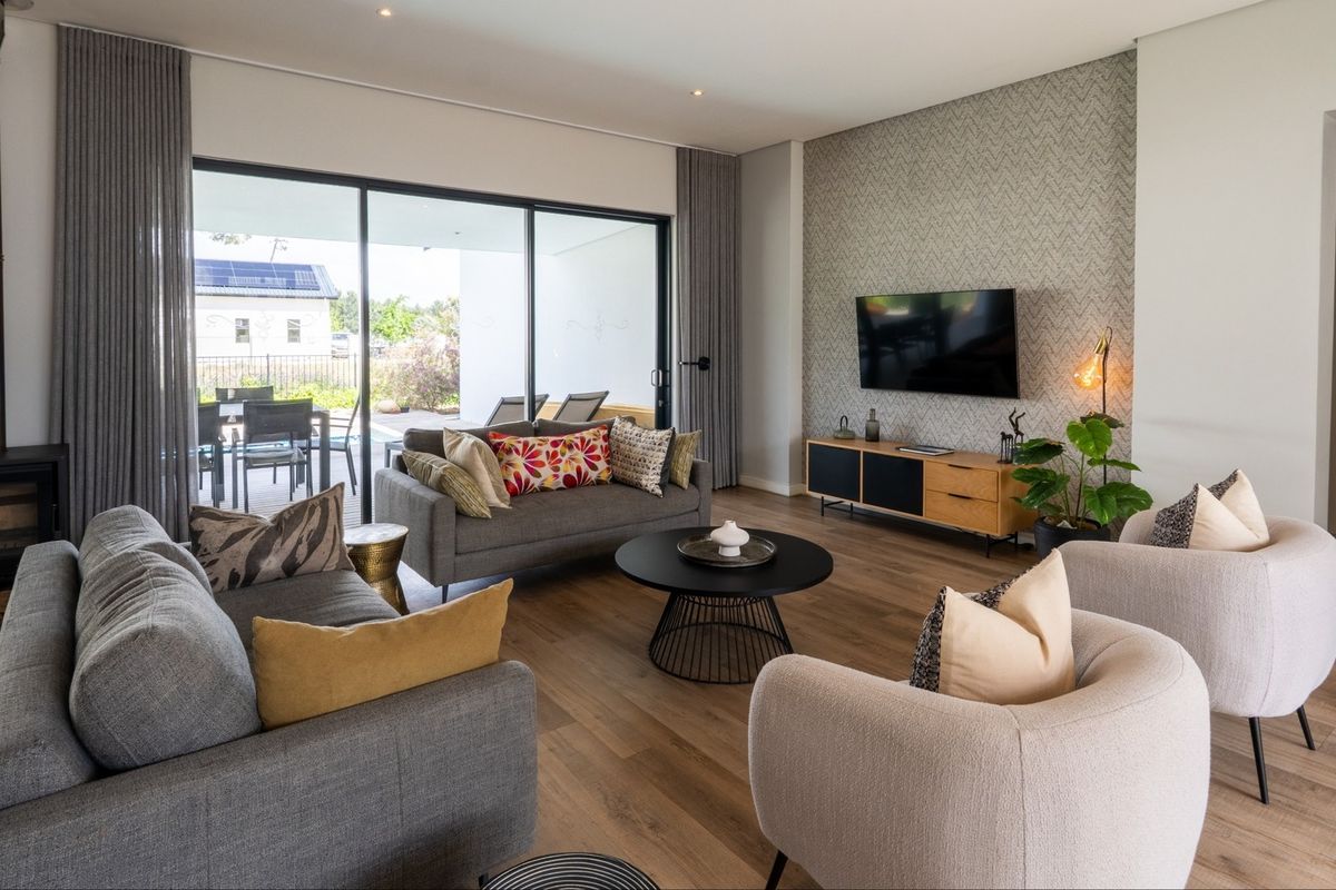 Modern living room featuring a wood-burning fireplace, large sliding glass doors leading to the patio, and stylish feature wallpaper.