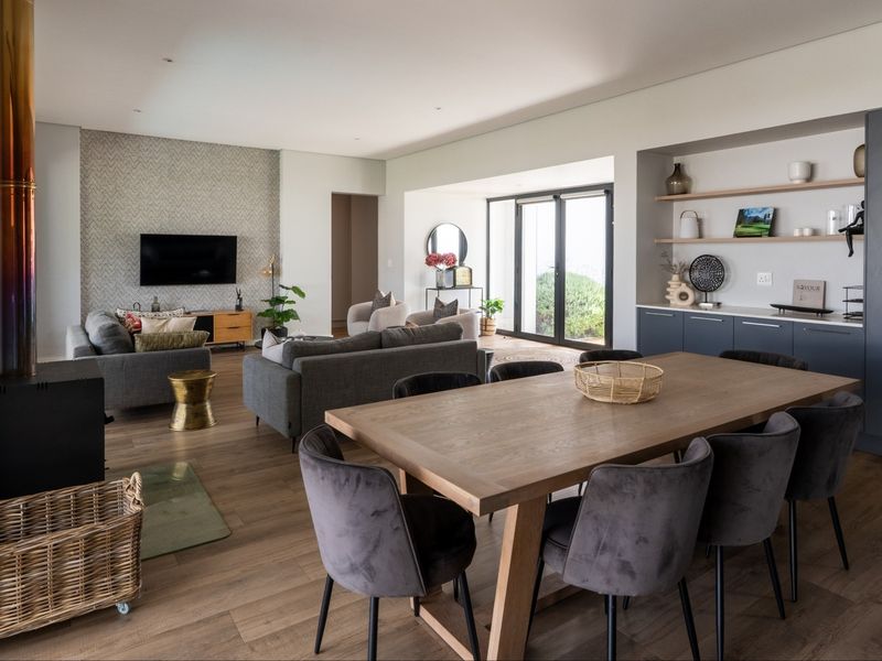 Spacious open-plan living and dining area featuring timber flooring, a modern wood-burning fireplace, and custom built-in cabinetry with integrated shelving.