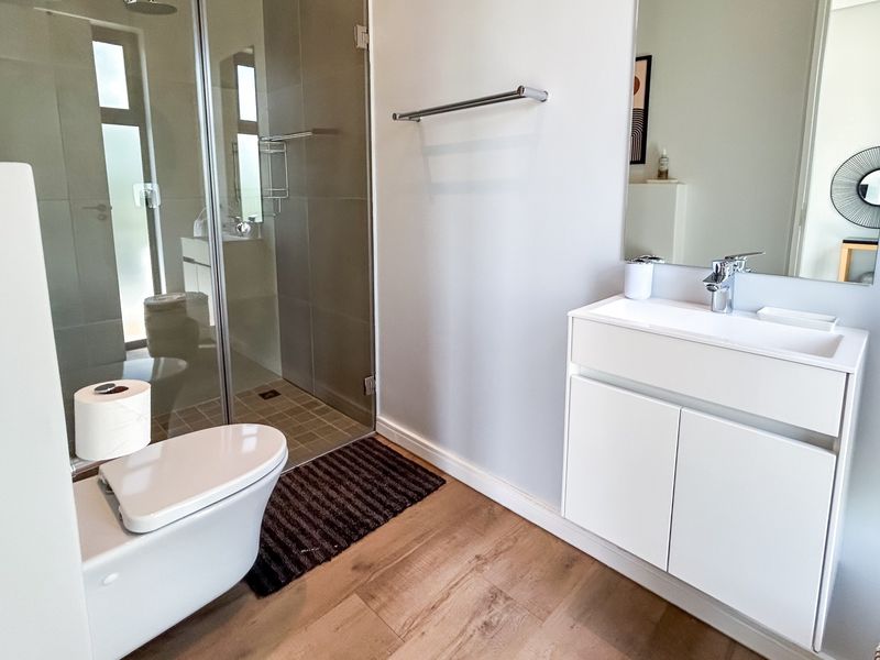 Modern bathroom featuring a walk-in shower with glass enclosure, wall-mounted vanity with basin, and contemporary fixtures.