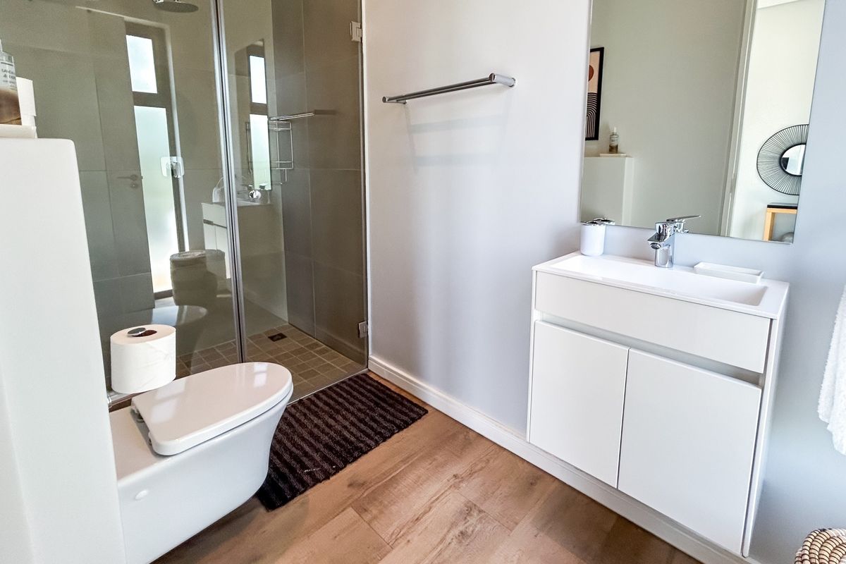 Modern bathroom featuring a walk-in shower with glass enclosure, wall-mounted vanity with basin, and contemporary fixtures.