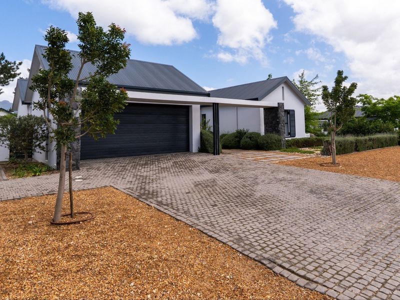 Modern residential property featuring a paved driveway, double garage, and contemporary architectural design with stone accents.