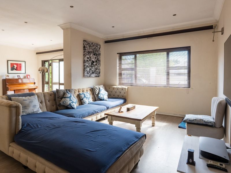 An open-plan living area featuring laminate flooring, recessed lighting, and a connected kitchen space with built-in cabinetry.