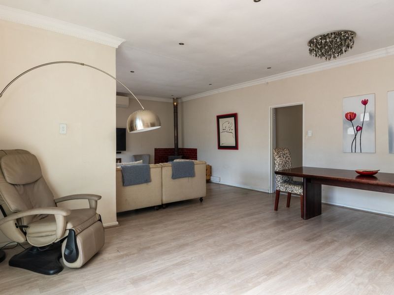 Spacious open-plan living and dining area featuring light laminate flooring, a wood-burning fireplace, and recessed lighting throughout.
