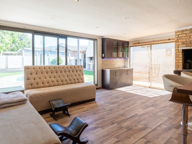 Spacious open-plan living area featuring a built-in kitchenette, brick fireplace, and large sliding doors providing seamless access to the outdoor pool area.