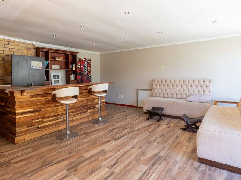 A well-appointed entertainment bar area featuring a custom wood-clad bar counter, exposed brick feature wall, and modern wood-look tile flooring.