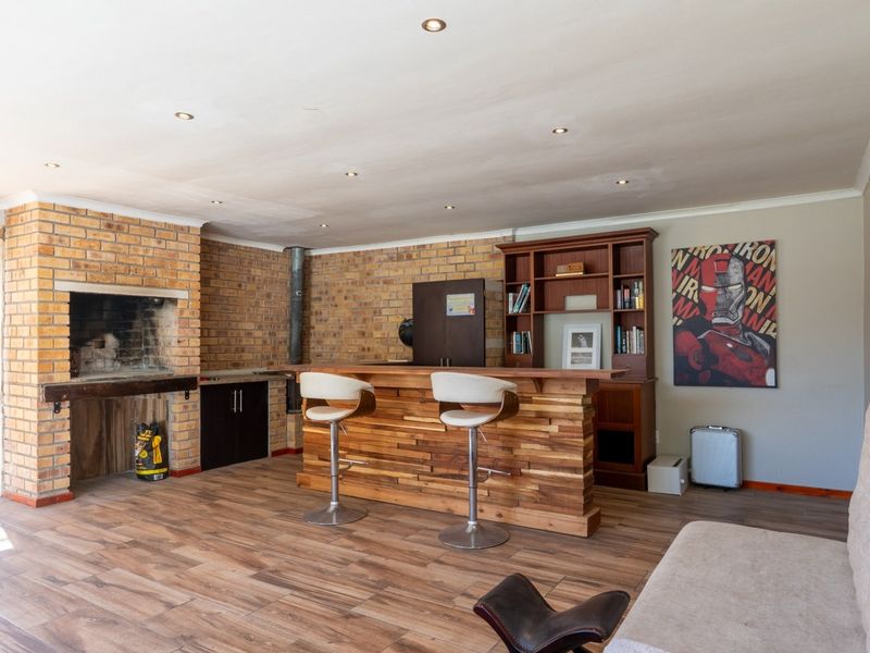Entertainment area featuring a built-in brick fireplace, custom wooden bar counter, and wood-look tile flooring with recessed lighting.