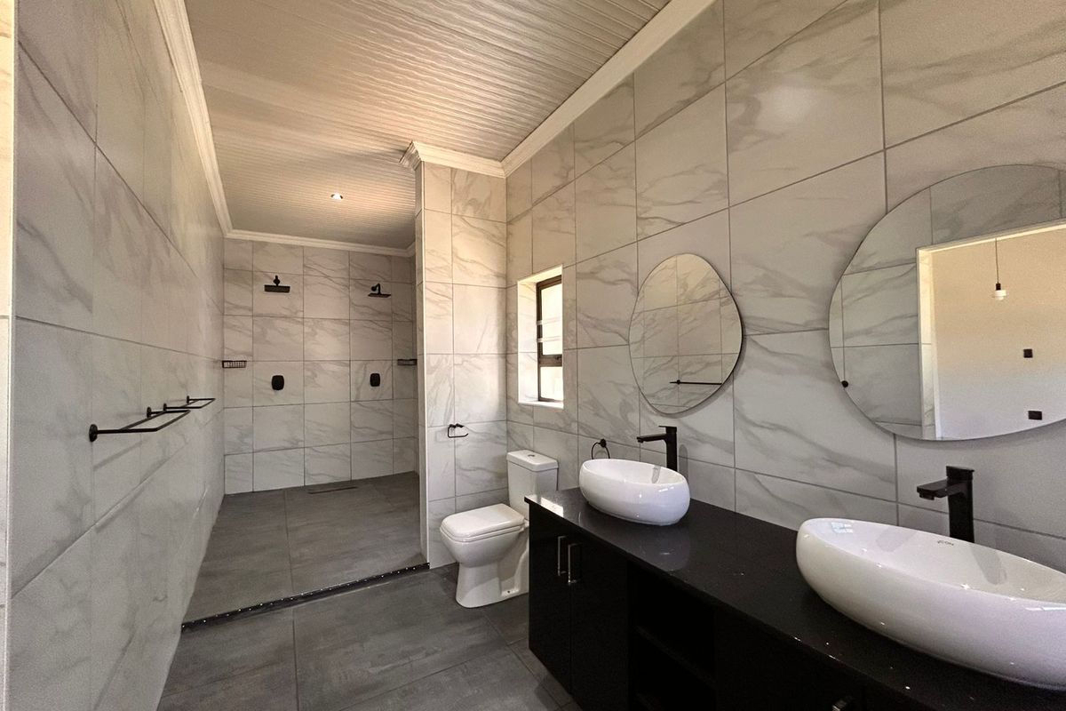 Modern bathroom featuring a double vanity with vessel sinks, a spacious walk-in shower with dual showerheads, and contemporary marble-look wall tiling.