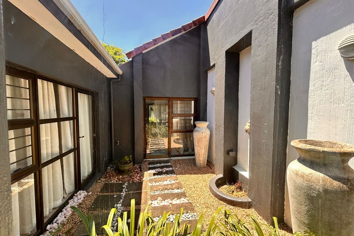 A private courtyard area featuring paved pathways, gravel landscaping, and direct access to the home through large glass sliding doors.