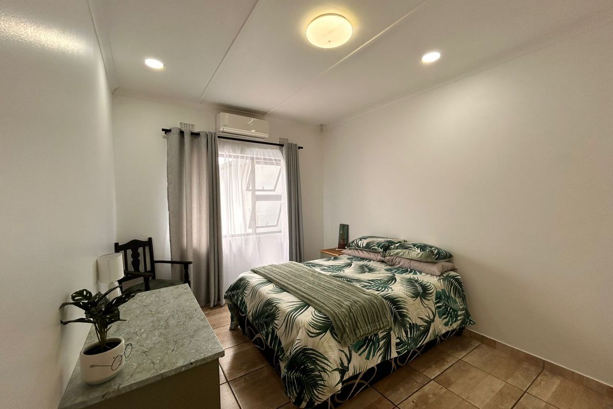 A well-maintained bedroom featuring tiled flooring, recessed lighting, and a wall-mounted air conditioning unit.