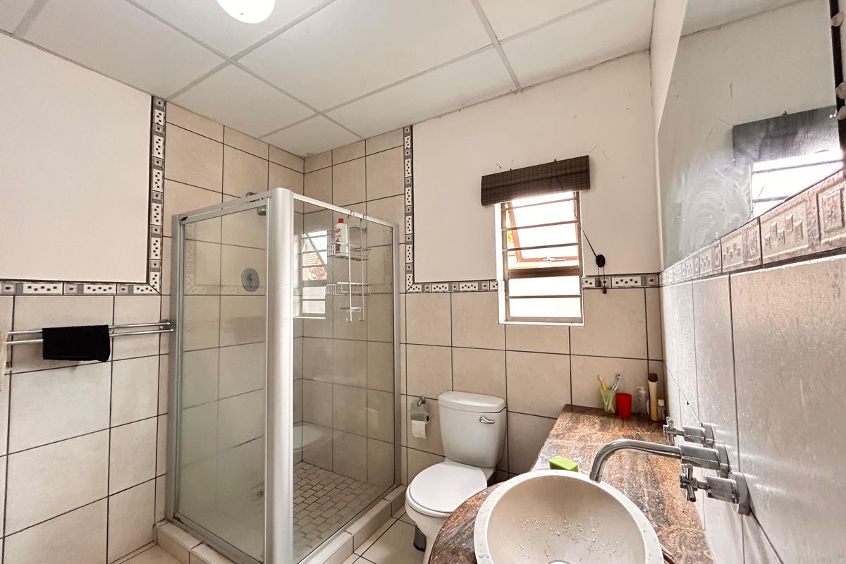 A functional bathroom featuring a glass-enclosed shower, a vanity with a basin, and tiled walls.