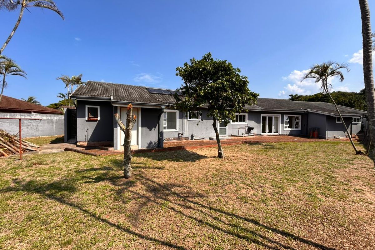 Rear view of the house featuring a tiled roof, solar panels, and a paved patio area leading out to a spacious garden.