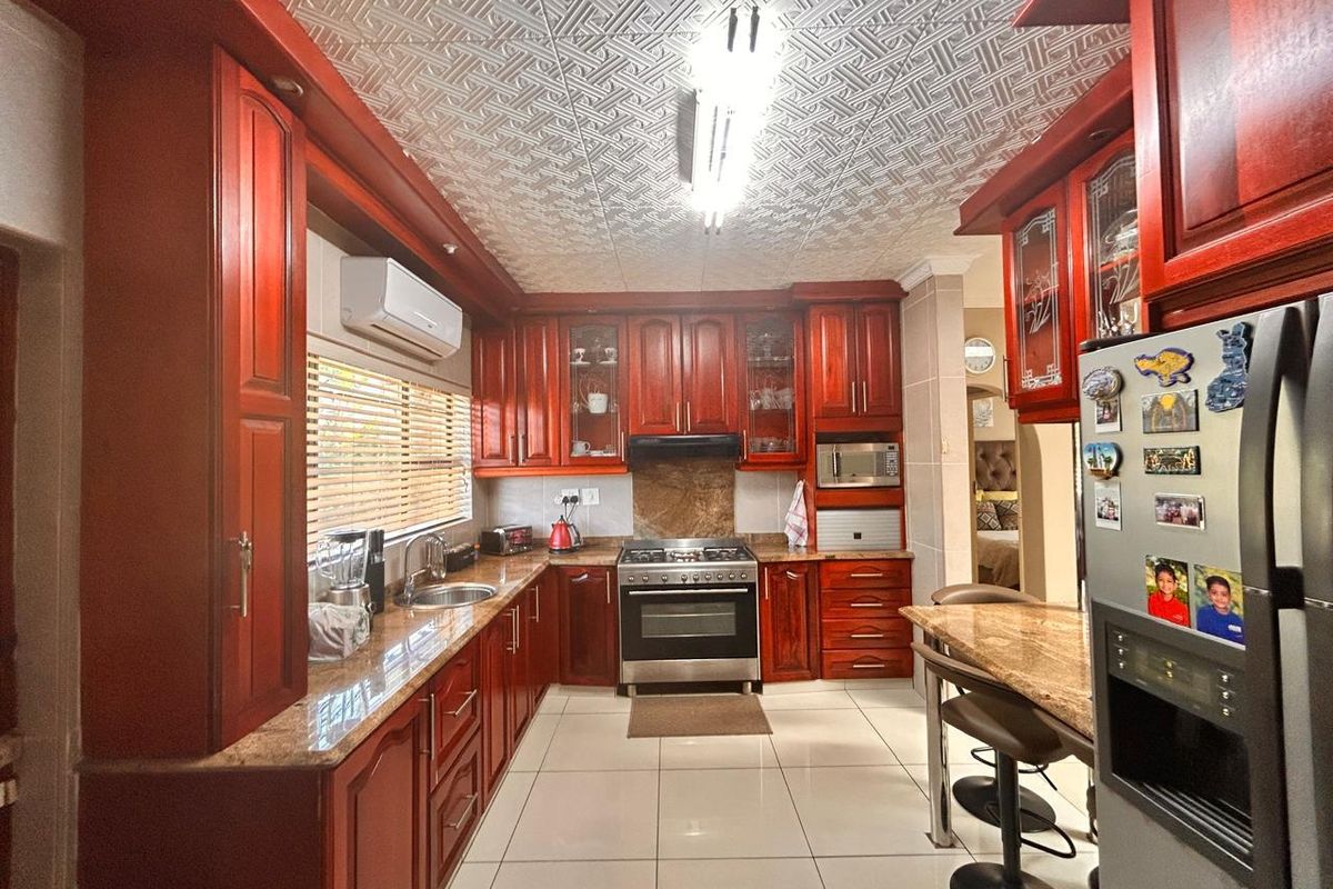 A traditional kitchen featuring rich wood cabinetry, granite countertops, a built-in oven with extractor fan, and tiled flooring.