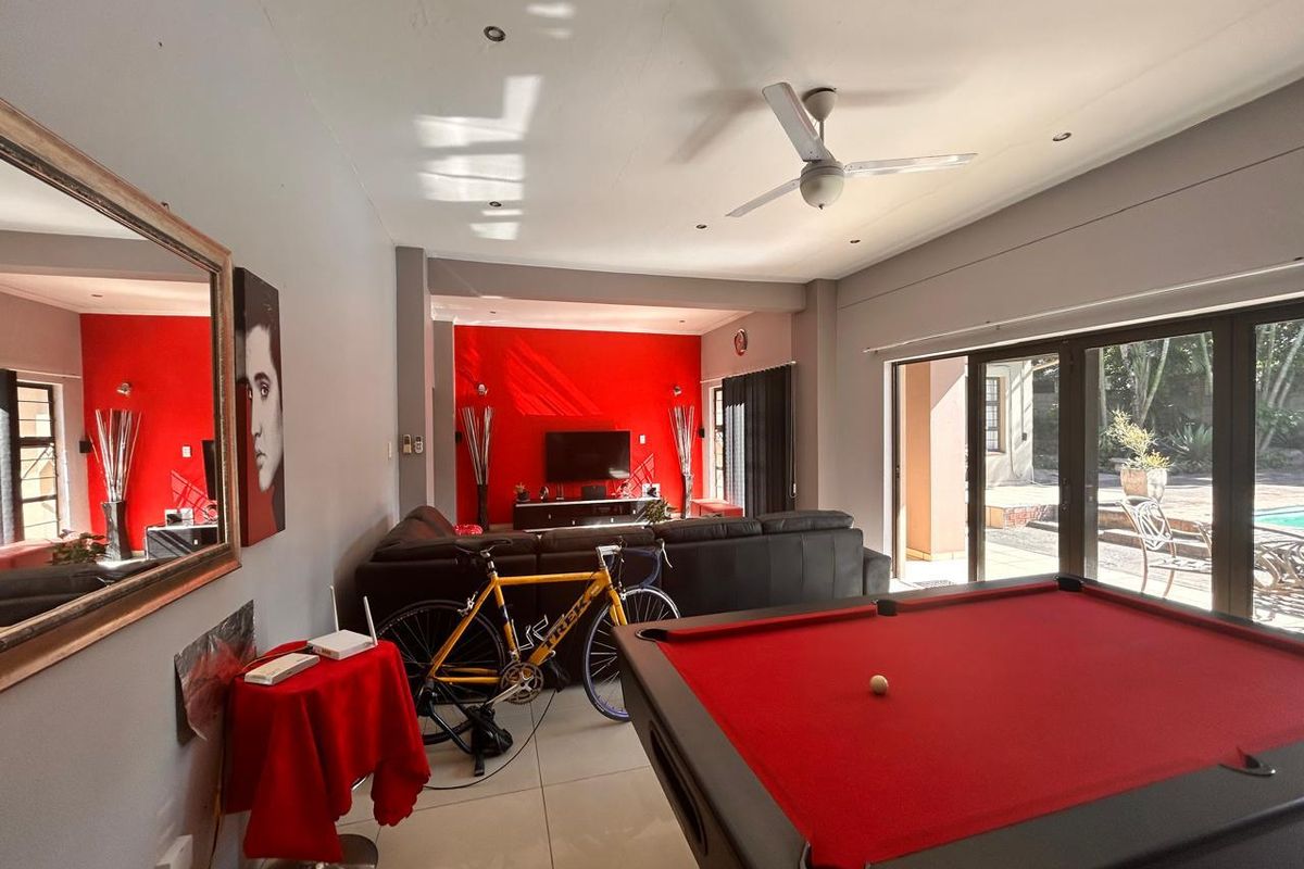 Spacious living area featuring tiled flooring, ceiling fan, and large glass sliding doors providing seamless access to the outdoor pool area.