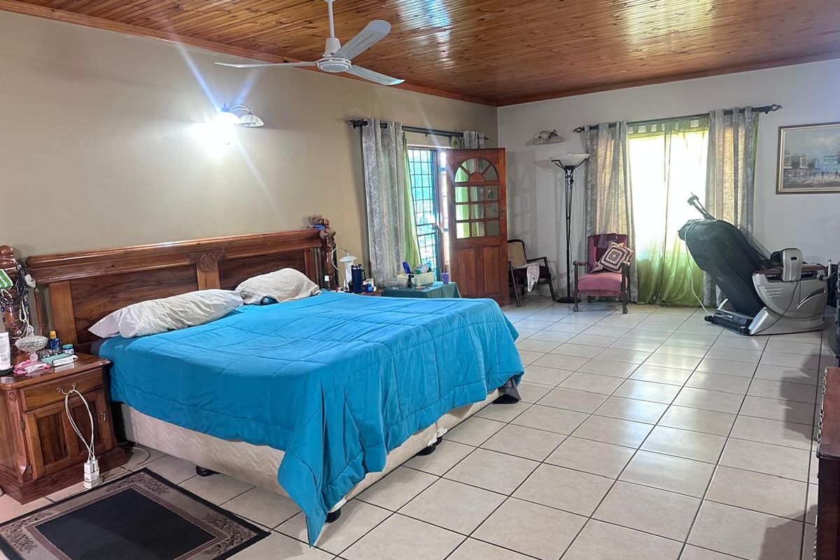 Spacious bedroom featuring ceramic floor tiles and a warm timber tongue and groove ceiling with an integrated ceiling fan.