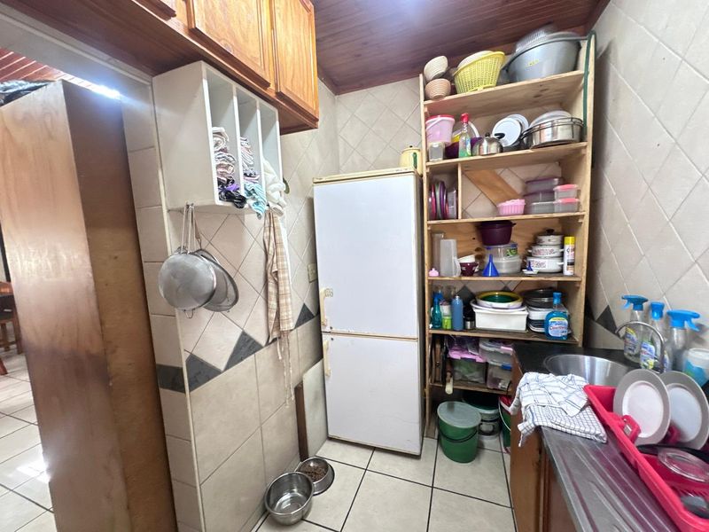 A functional scullery area featuring tiled walls, timber ceiling, and a stainless steel sink, providing additional utility and storage space.
