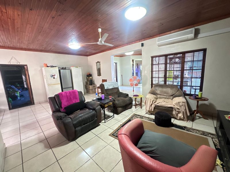 Spacious living area featuring a timber-clad ceiling, tiled flooring, and a split-system air conditioner, offering a comfortable and functional layout.