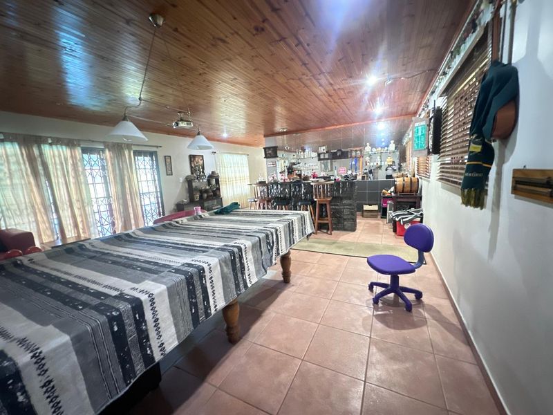 Spacious entertainment area featuring a built-in bar, timber ceiling, and tiled flooring, providing a functional space for social gatherings.