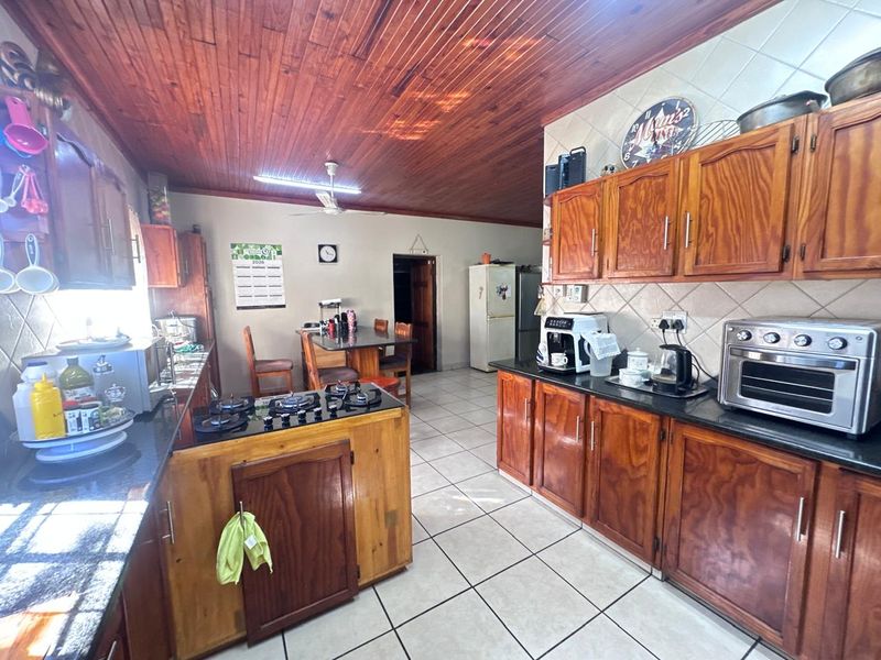 Open plan kitchen and dining area featuring wooden cabinetry, granite countertops, a gas hob, and a distinctive wooden ceiling.