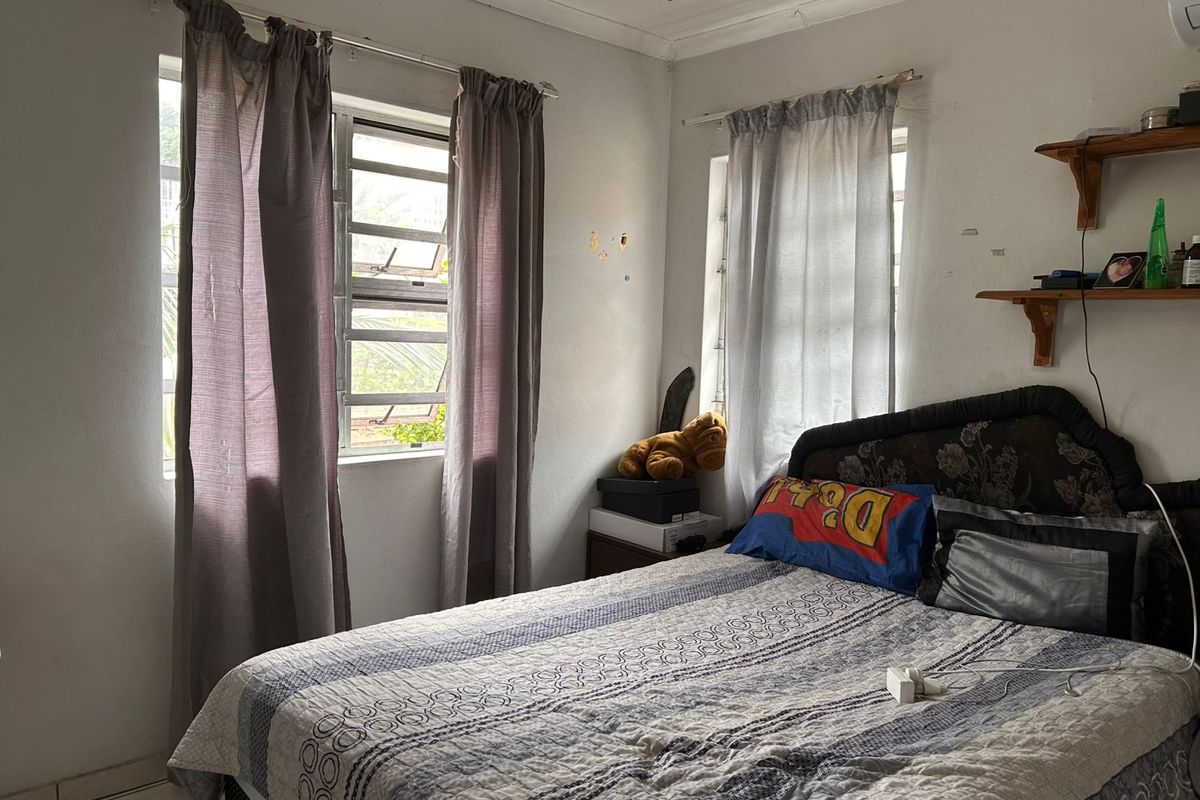 A bedroom featuring dual windows with louvered glass panes, crown molding, and wall-mounted shelving.