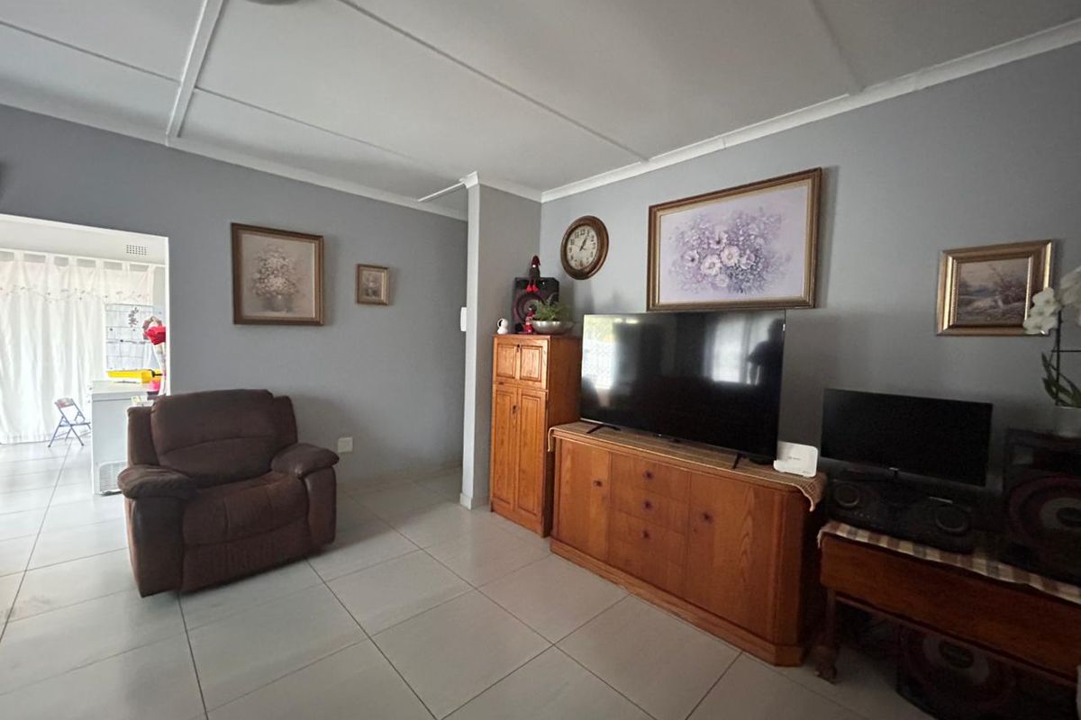 A living room featuring tiled flooring and a neutral wall finish, with an open transition to an adjacent kitchen area.