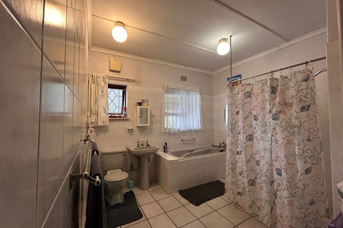 A functional bathroom featuring a pedestal basin, a built-in bathtub with shower combination, and tiled flooring.