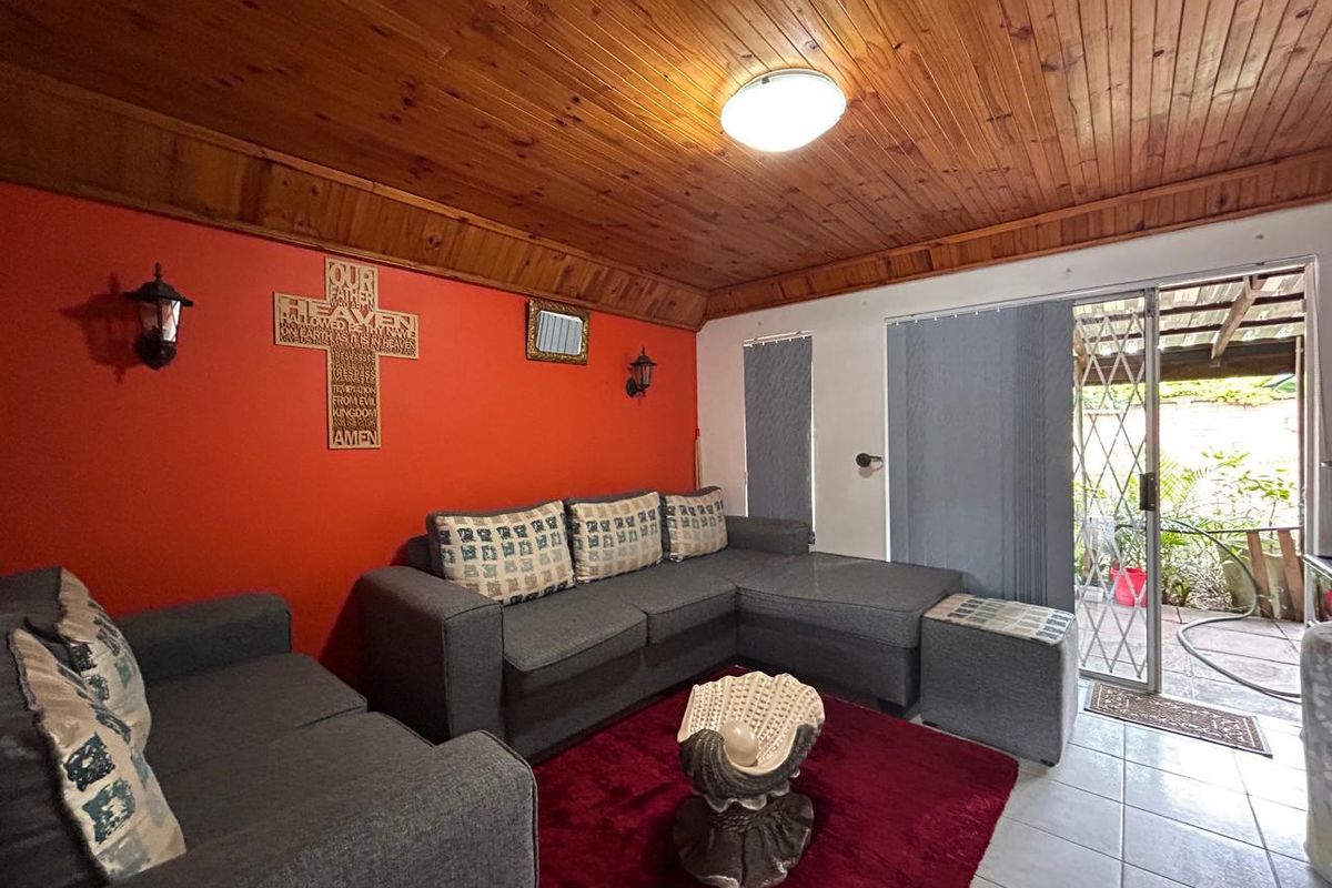 Living room featuring a timber-clad ceiling, tiled flooring, and sliding glass door access to an outdoor patio area.