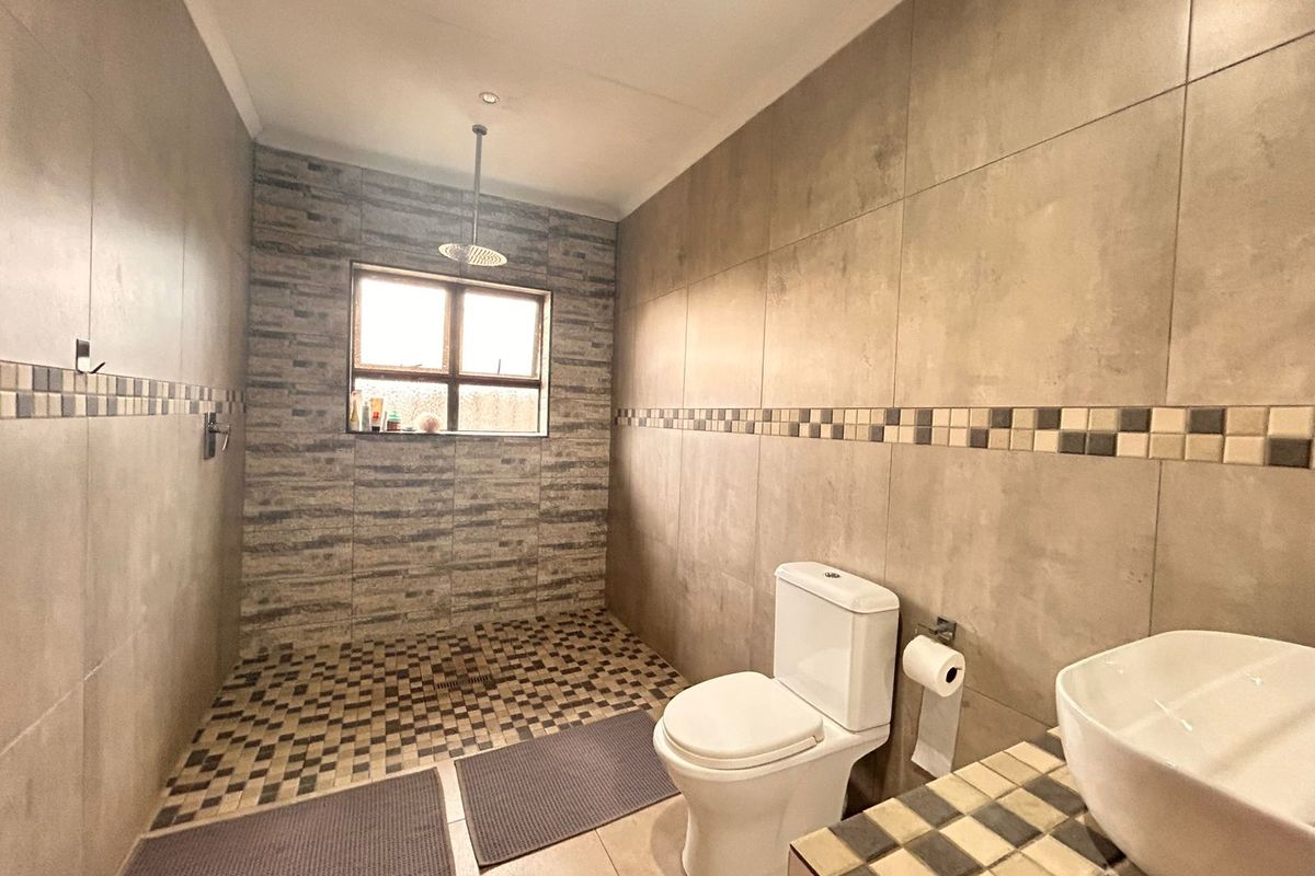 Modern bathroom featuring a walk-in shower with rainfall showerhead, tiled walls, and a contemporary vessel sink vanity.