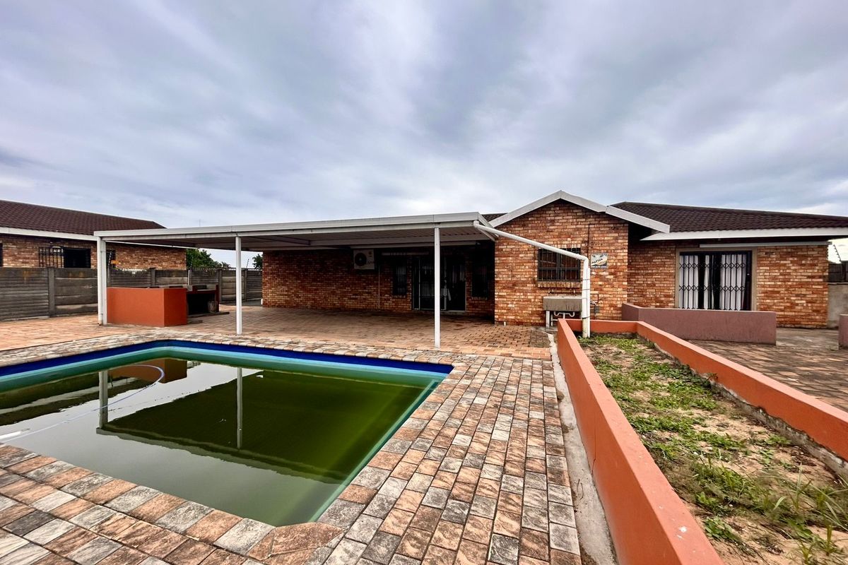 Rear exterior view featuring a swimming pool, covered patio area, and brick-built garden planters, showing potential for outdoor renovation and landscaping.