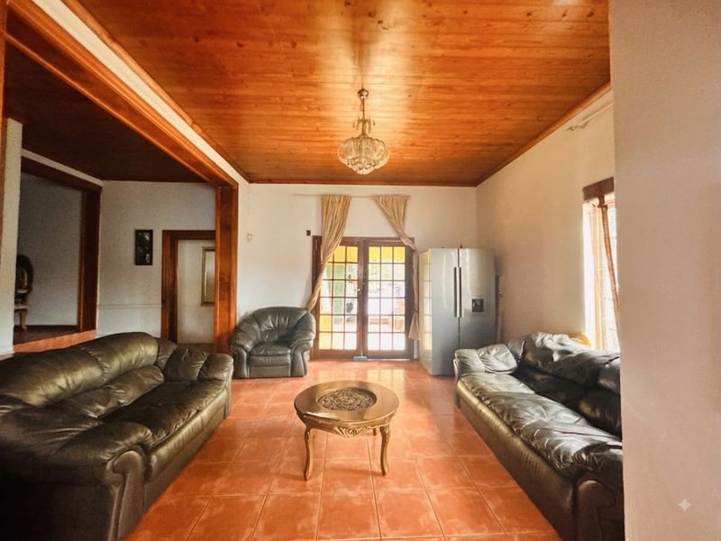 Spacious living room featuring a warm timber-clad ceiling, tiled flooring, and direct access to the outdoors through classic french doors.