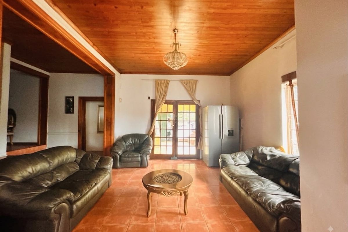 Spacious living room featuring a warm timber-clad ceiling, tiled flooring, and direct access to the outdoors through classic french doors.