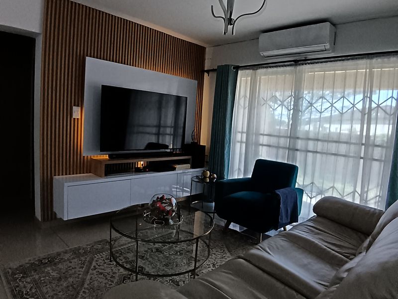 A well-maintained living room featuring a modern slatted wood accent wall, built-in media cabinetry, and a split-system air conditioning unit.