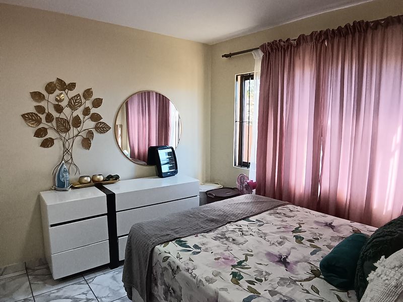 A bedroom featuring tiled flooring and a window with curtain rod installation.