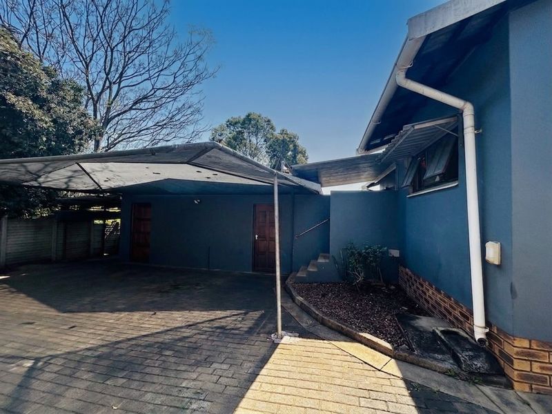 Exterior view of the property featuring a paved driveway, a covered carport, and direct access to the side entrance.