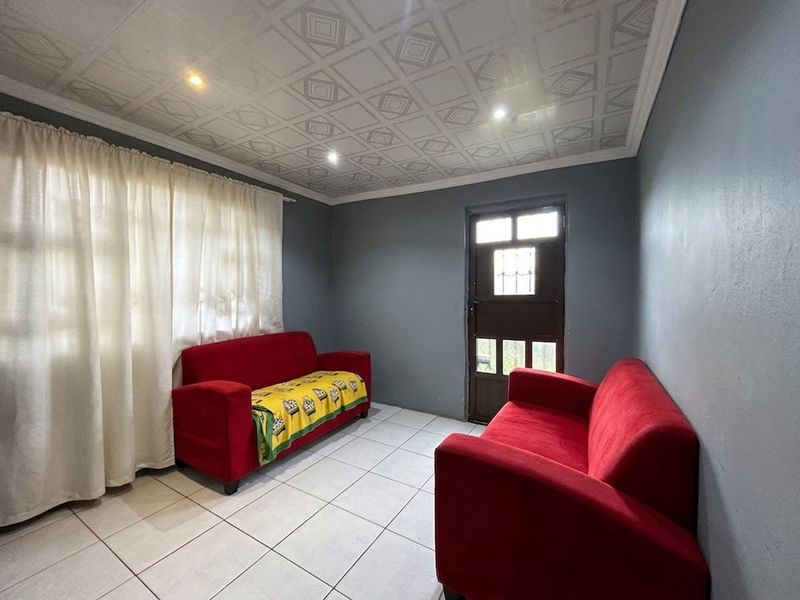 A living room featuring tiled flooring, recessed downlights, and a decorative patterned ceiling, with direct access to the exterior.