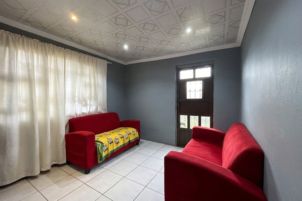A living room featuring tiled flooring, recessed downlights, and a decorative patterned ceiling, with direct access to the exterior.