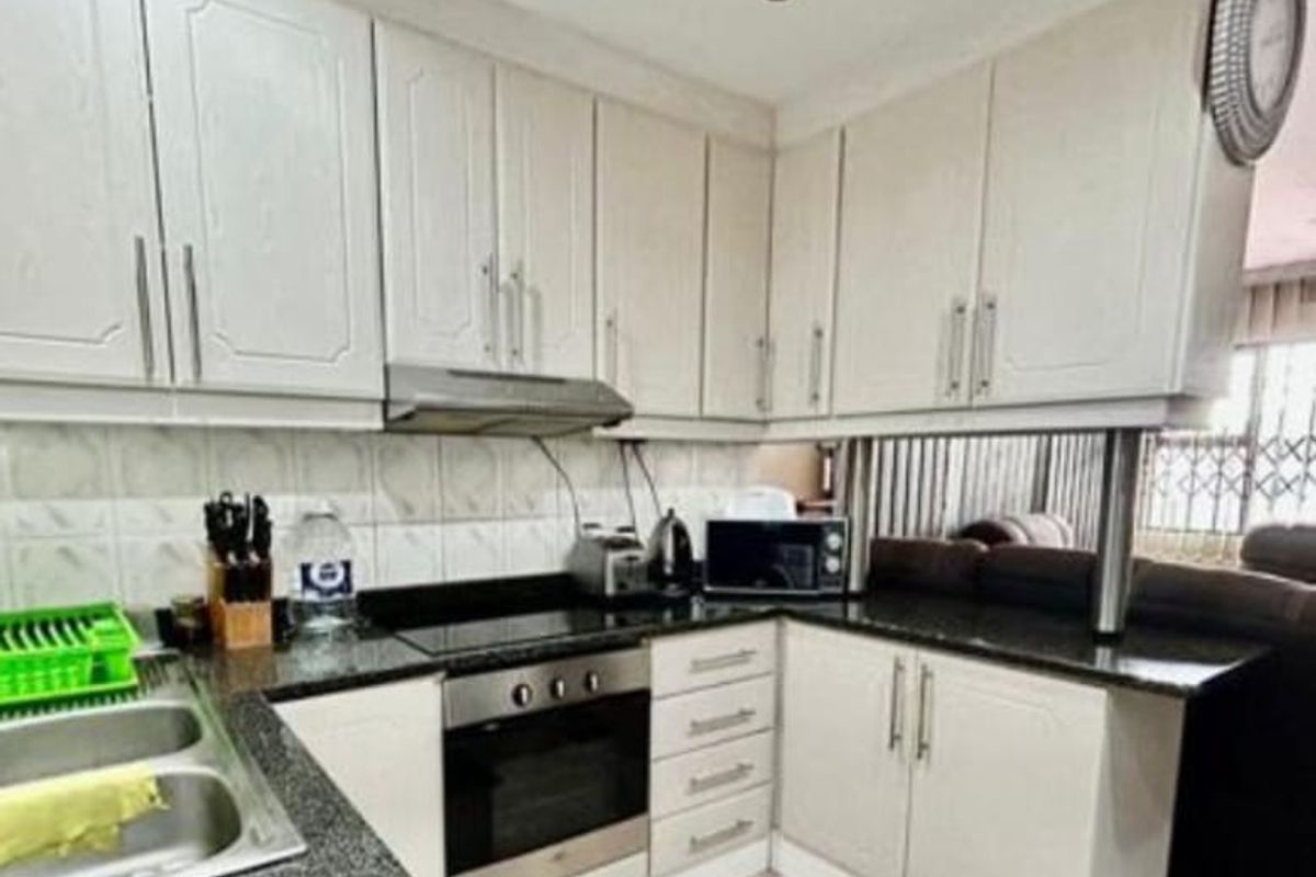 A functional kitchen featuring white cabinetry, granite countertops, a built-in oven, electric hob, and a tiled backsplash.