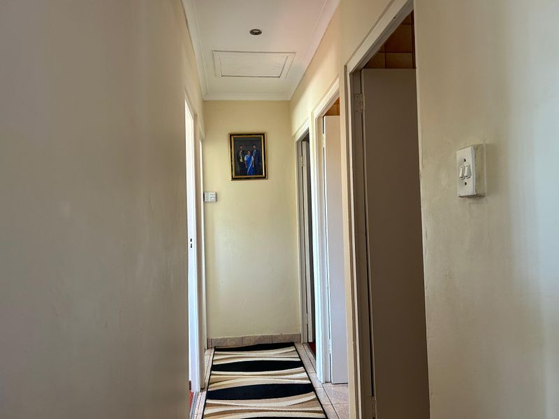 A functional hallway featuring tiled flooring, recessed ceiling lighting, and access to multiple rooms via standard doorways.