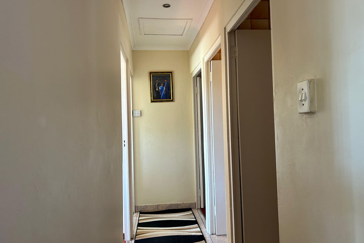 A functional hallway featuring tiled flooring, recessed ceiling lighting, and access to multiple rooms via standard doorways.