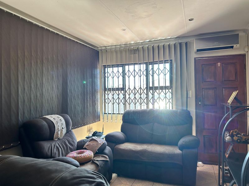 A living room featuring tiled flooring, recessed lighting, an air conditioning unit, and security gates on the windows.