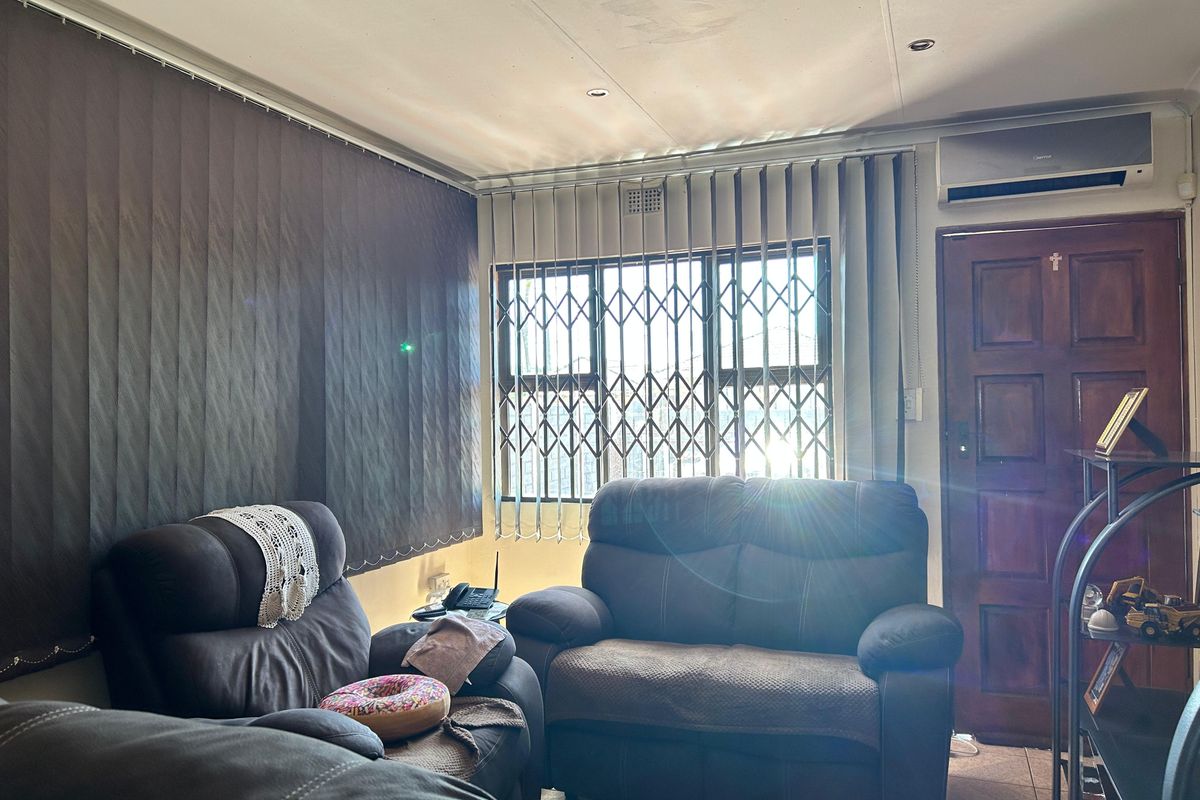 A living room featuring tiled flooring, recessed lighting, an air conditioning unit, and security gates on the windows.