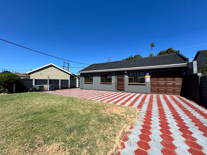 Front view of a single-story house featuring a paved driveway, attached garage, and a well-maintained lawn area.