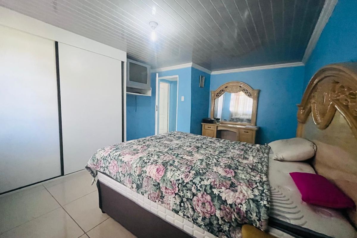 A bedroom featuring tiled flooring, a panelled ceiling, and a built-in wardrobe.