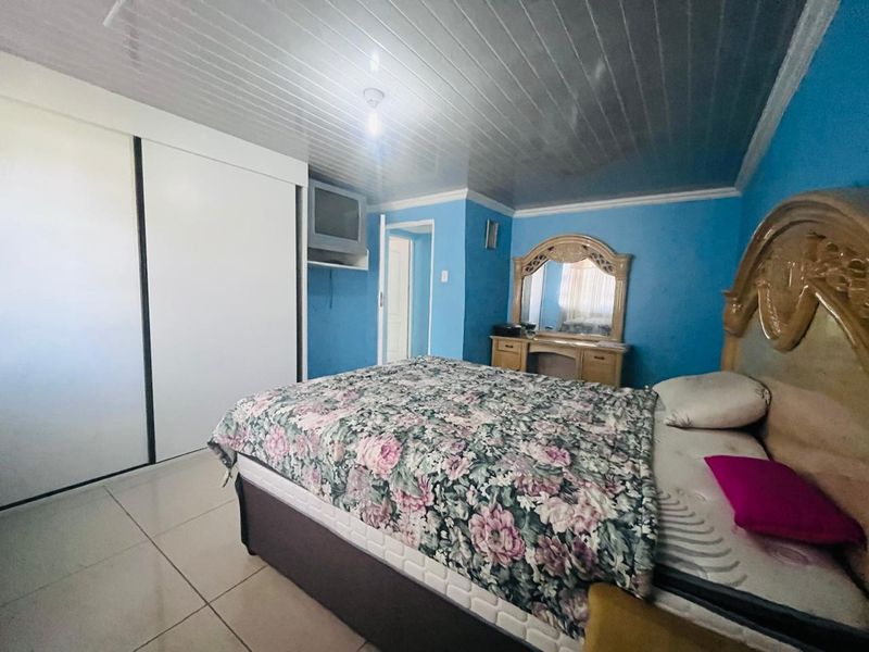 A bedroom featuring tiled flooring, a panelled ceiling, and a built-in wardrobe.