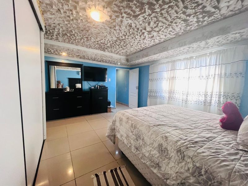 A bedroom featuring tiled flooring, a built-in wardrobe, and a distinctive textured ceiling finish.